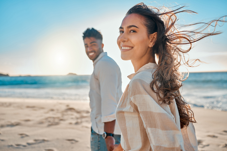 happy couple holding hands and strolling along the beach