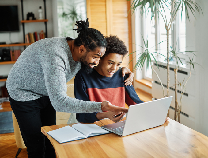 father and teenaged son looking at a laptop