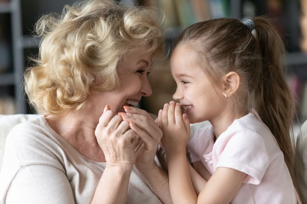 Close up of funny grand daughter joyful grandmother telling secrets