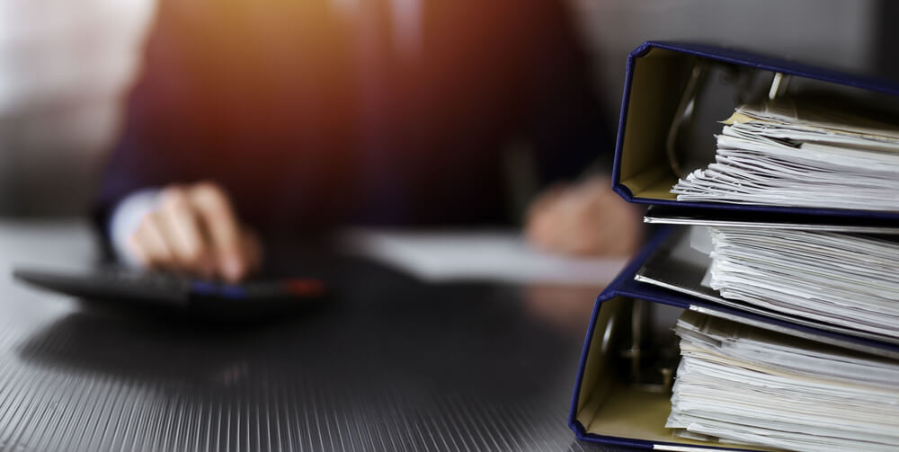 Binders with papers are waiting to be processed by unknown man